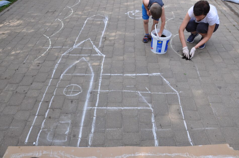 Dwie osoby rysują kredą szkic rysunku na chodniku