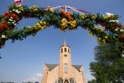 Kościół na tle błękitnego nieba i kolorowa brama ułożona z kwiatów